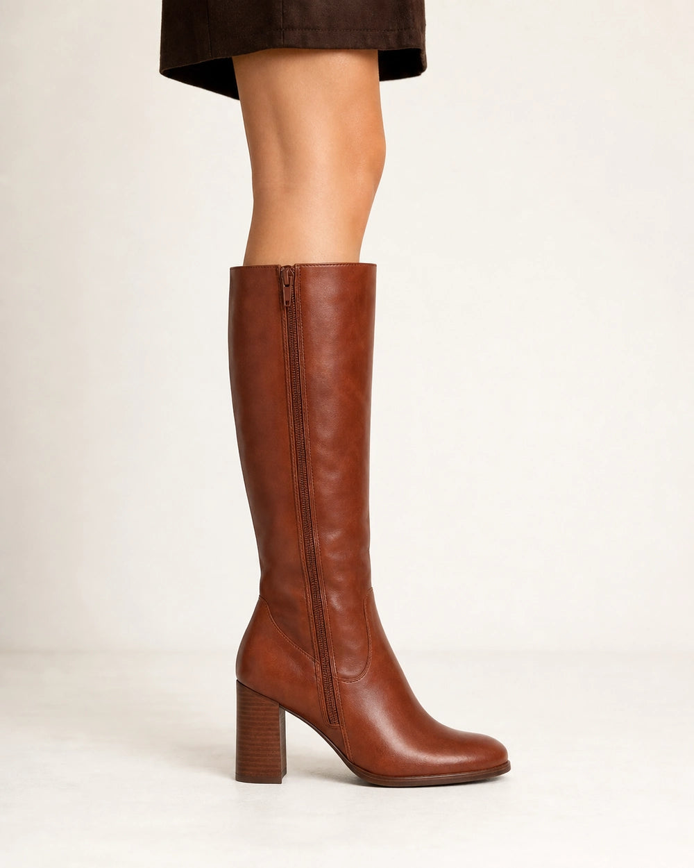 Women's cognac-brown knee-high boots with a sculpted block heel, lateral profile.