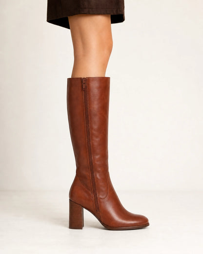 Women's cognac-brown knee-high boots with a sculpted block heel, lateral profile.