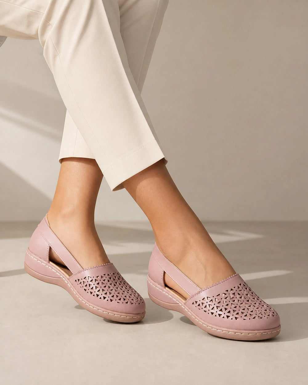 Women's light pink perforated slingback shoes, worn front three-quarter view.