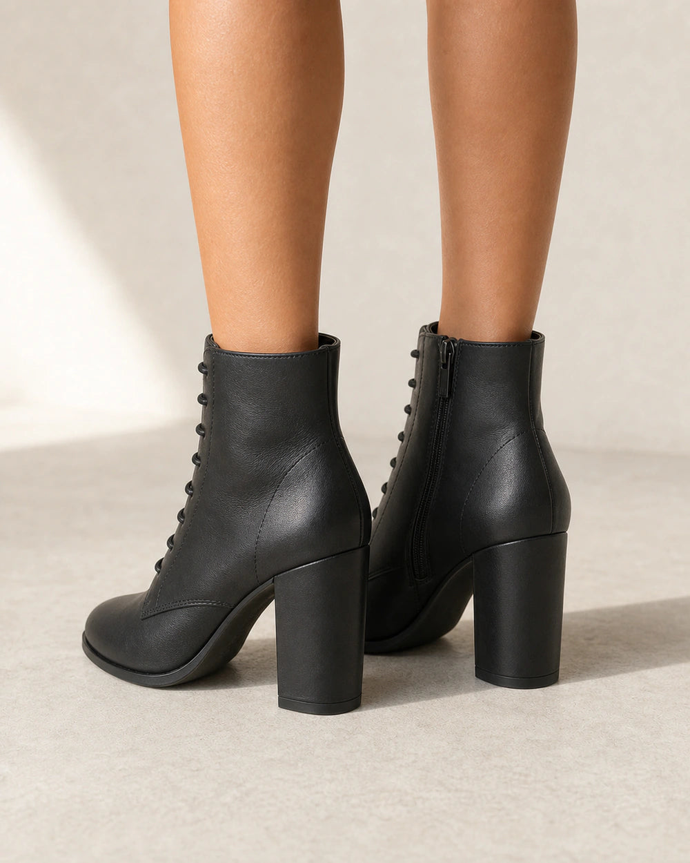 Women's black lace-up high-heel ankle boots, rear view.