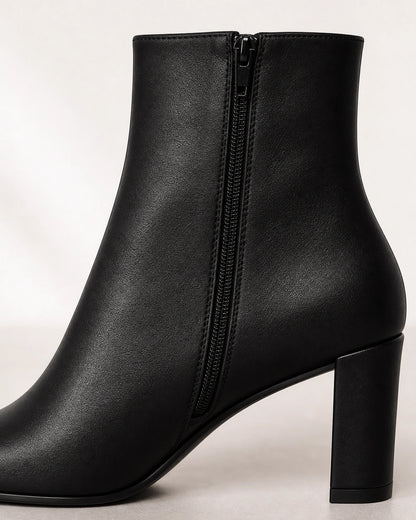 Women's black pointed-toe high-heel ankle boots, construction detail.