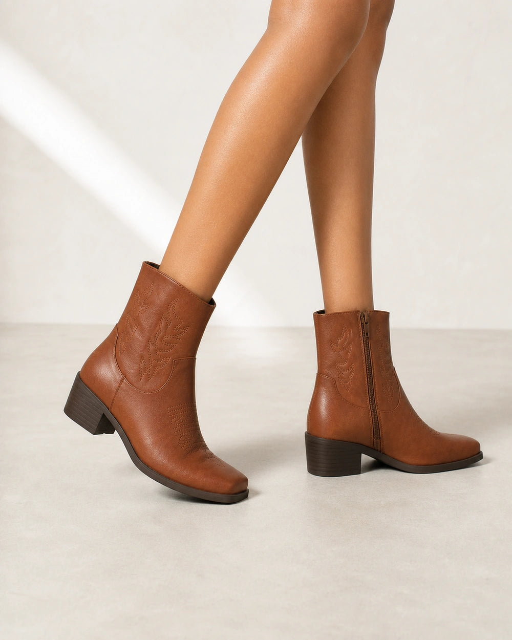 Women's brown square-toe western ankle boots, walking view.