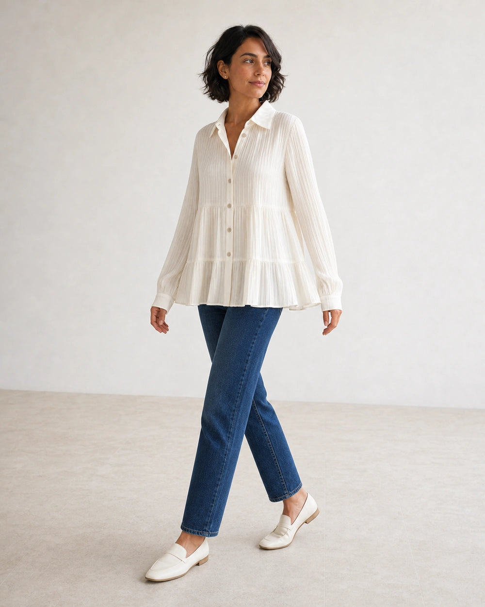Women's milk-white pleated peplum shirt in a walking movement view.