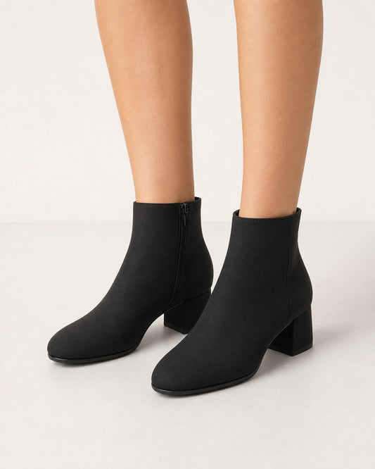 Women's minimalist black block-heel ankle boots, front three-quarter view.