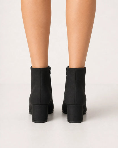 Women's minimalist black block-heel ankle boots, rear view.