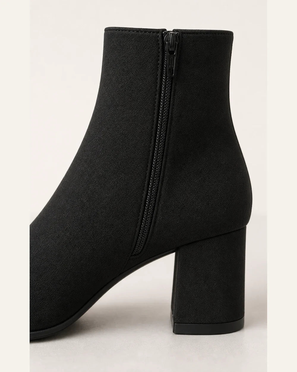 Women's minimalist black block-heel ankle boots, construction detail.
